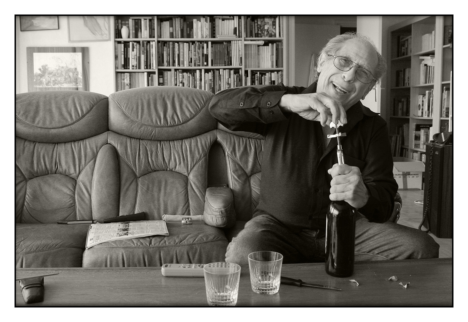 Portrait de Yves Manciet chez lui en train d'ouvrir une bouteille de vin